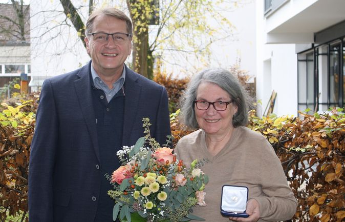 Frau hält geöffnetes Medaillenetui mit Martinusmedaille und Blumen neben einem Mann