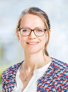 Porträt einer lächelnden Frau mit Brille und gemustertem Blazer