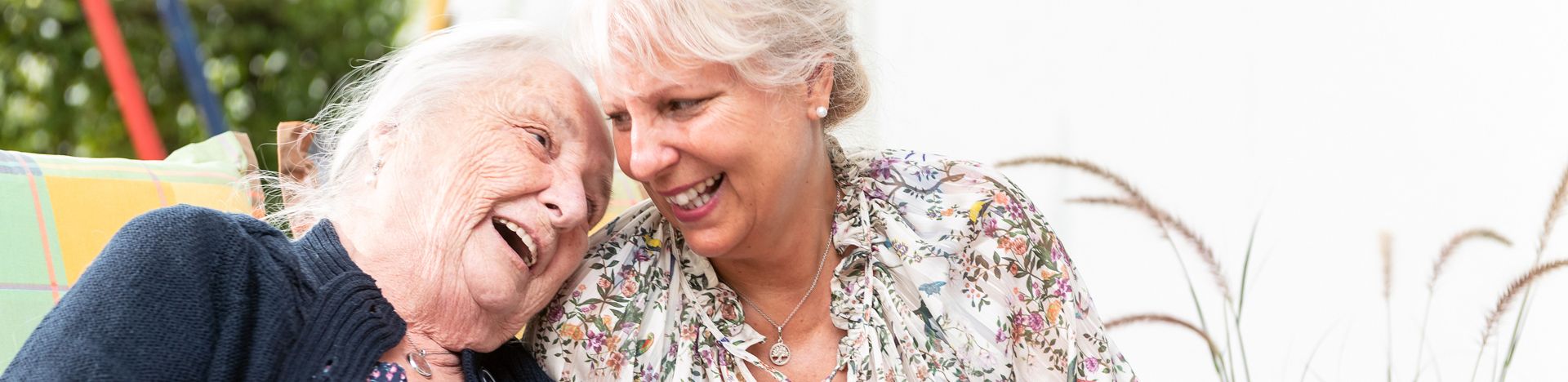 Ältere Frau und jüngere Frau lachen und halten Garn und bunte Decke